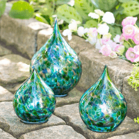 Hand blown blue and green solar lights in teardrop shapes, 3 on a garden path